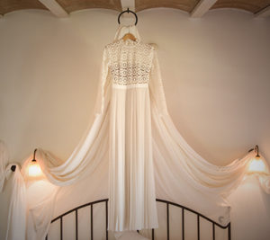 wedding dress hung above bed