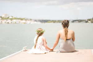 woman and girl by water holding hands