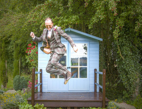 man jumps in front of garden shed - English Wedding