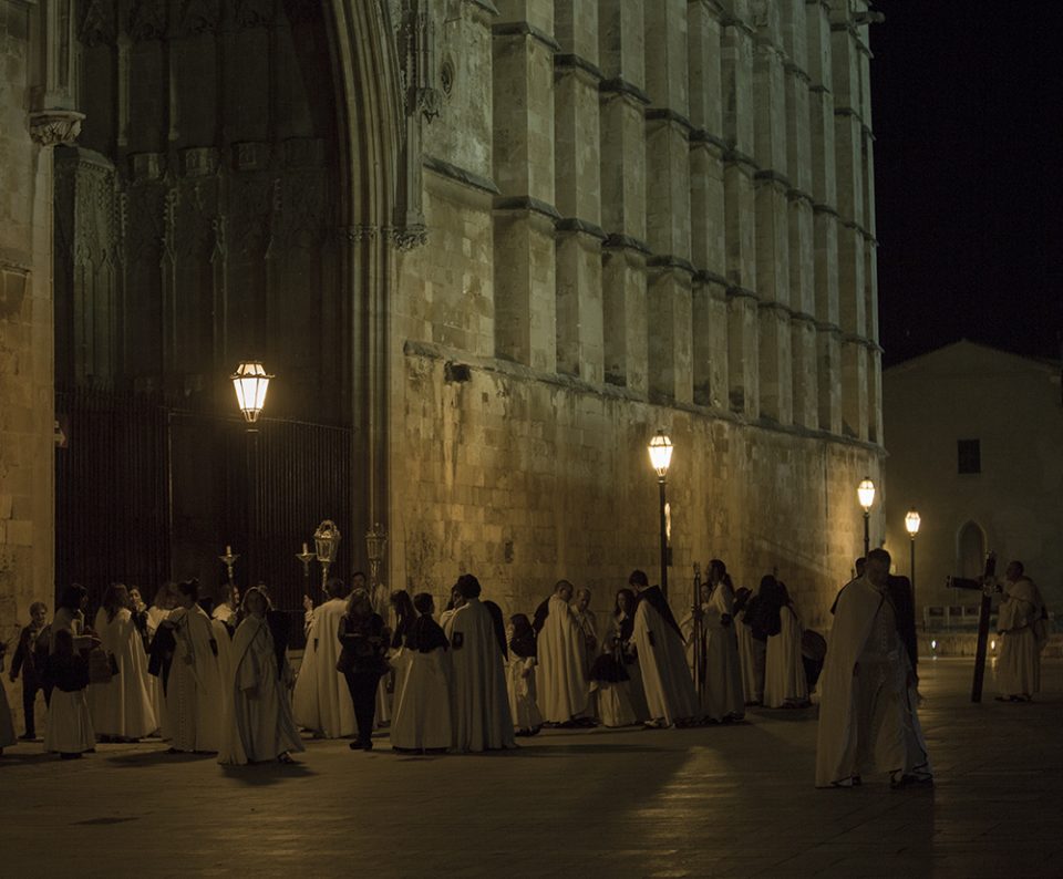 Religious people in costume stand outside Palma Cathedral