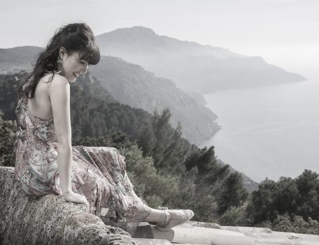 woman on wall overlooking mountains and sea - Portrait Photography