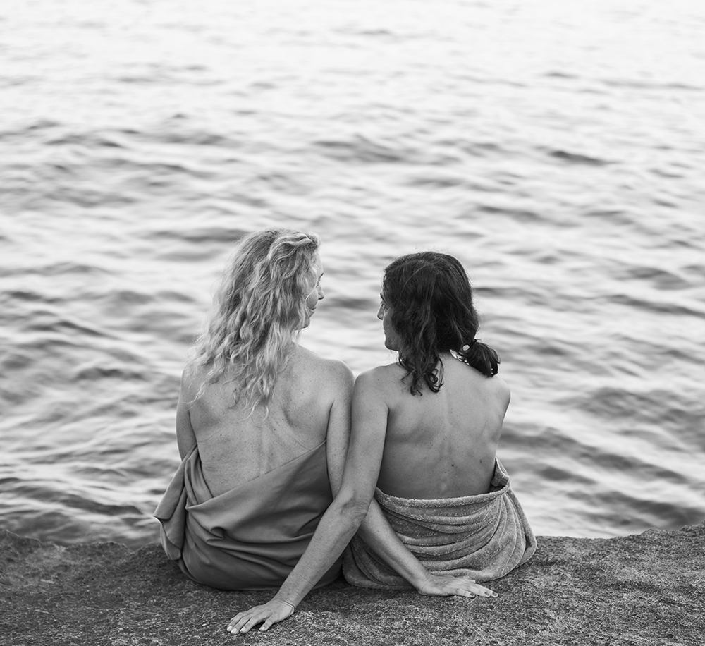 two girls sit by water